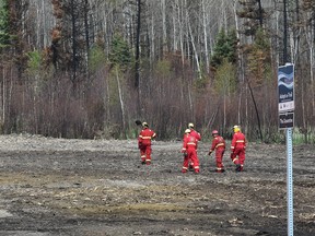A crew of firefighters from Calgary walking along what use to be a park trail system in the northend of the Timberlea area in Fort McMurray, after checking for hot spots along a fire guard behind homes, June 2, 2016. Ed Kaiser/Postmedia Network