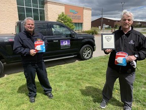 Jeff Balkwill, (left) a Brant County Fire Prevention officer and retired Brantford firefighter John Gignac with an award and CO alarms.
