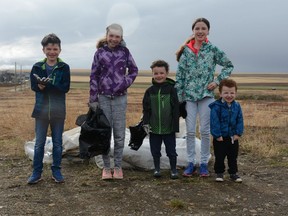 Linden (from left to right), Evalene, Preston, Natalia, and Nolan Andrews stand with garbage bags at the ready to clear debris from a field behind their home. Photo by Riley Cassidy