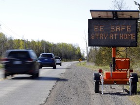 Vehicles pass a sign on Shannonville Road in Tyendinaga Township Wednesday. Ontario's stay-at-home order is to continue until at least June 2.