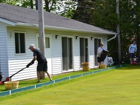 Volunteers at the St. George Lawn Bowling Club work to get the green ready for reopening on Saturday.