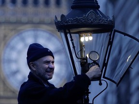 British Gas engineer Martin Caulfield services and cleans a gas lamp in front of Big Ben in London in a photo from 2011.
