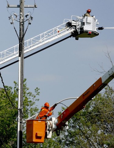 A Hydro One worker disconnects power to a building on fire at Harold's Demolition on Wednesday morning, while a firefighter continues to attack the blaze from the air. (RONALD ZAJAC/The Recorder and Times)