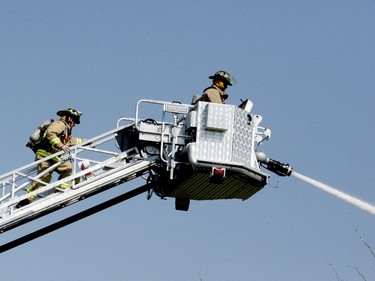 A firefighter walks up an aerial ladder to join a colleague battling a blaze on Hamilton Street from above the trees. (RONALD ZAJAC/The Recorder and Times)