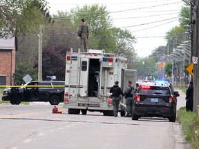 A member of the OPP bomb disposal unit stands on top of a police vehicle to servey the scene where a suspicious package was found on at property on Park Avenue West in Chatham on Monday, May 10. Ellwood Shreve/Postmedia Network