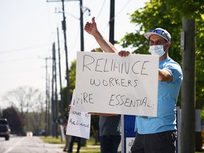 Matt Martinho, a Unifor Local 1999 worker locked out from Reliance Home Comfort in Chatham, looks for support from a passing vehicle on Riverview Drive on May 14, 2021.