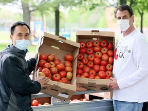 Come Together CK volunteers Yao Zhang (left) and Tim Haskell were giving away free tomatoes on Baldoon Road in Chatham on May 5. Mark Malone/Postmedia Network