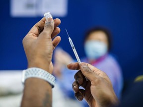 FILE: A healthcare worker prepares an intravenous dose of COVID-19 vaccine.