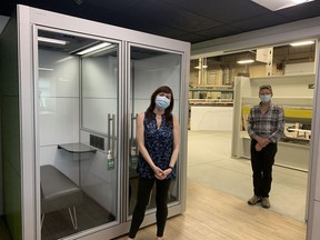 SnapCab employees Allison Grange and John Weima stand in front of the new Isolation Pod at SnapCab's Kingston office.