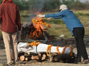 Relatives perform the last rites before the cremation of a loved one who died due to COVID-19 at a cremation ground in Allahabad on Tuesday.