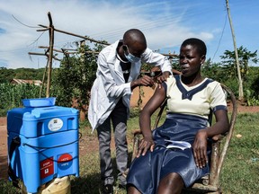 A medical health worker injects the Oxford/AstraZeneca COVID-19 vaccine to a woman as they visit door-to-door to deliver the vaccines to people who live far from health facilities in Siaya, Kenya, on Tuesday.