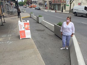 Lana LeBlanc stands in a parking area in front of her store, Birds 'n Paws, where cement abutments have been installed, blocking her curbside pickup area.