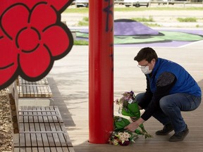 Boyle Street's executive director Jordan Reiniger arranges three bundles of flowers at a memorial in Kinistinâw Park, 96 Street and 103 Avenue in Edmonton on Tuesday, May 25, 2021. Ambulance crews were called to the park May 21, 2021, where they found three people in medical distress. Paramedics determined they were in cardiac arrest and tried to resuscitate them, but all three died at the scene.