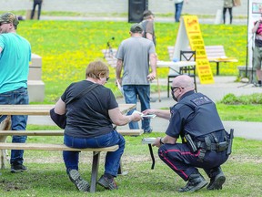 A Sault Ste. Marie Police Service officer hands out a ticket during an anti-lockdown protest at Bellevue Park Saturday. Bob Davies/Postmedia Network