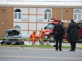 Sarnia police officers are shown at the scene of a single-vehicle crash Friday morning on London Line where a middle-aged man died. Yellow police tape was up around a damaged Jeep in the parking lot of the Versatile Inn and Goldie's Family Restaurant.