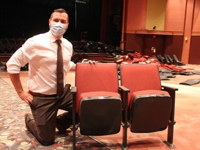 Brian Austin Jr., executive director of the Imperial Theatre in Sarnia, kneels next to one of the sets of theatre seats being sold as a fundraiser. The 600 seats are being replaced as part of ongoing renovations at the downtown theatre.