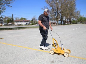 Arena employee Patrick St. Amour paints lines at the Garson arena parking lot in Garson, Ont. on Tuesday May 18, 2021. John Lappa/Sudbury Star/Postmedia Network