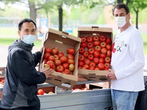 Come Together CK volunteers Yao Zhang, left, and Tim Haskell give away free tomatoes on Baldoon Road in Chatham, Ont., on Wednesday, May 5, 2021. Mark Malone/Chatham Daily News/Postmedia Network