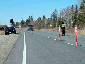 A Kenora OPP officer directs traffic entering Ontario at the rest stop at the provincial border with Manitoba on Monday, April 19.