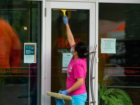 A worker in a COVID-19 masks cleans the windows of Rëdl Kitchen on 124 Street in Edmonton, on Friday, May 28, 2021.