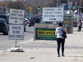 A person walks past pandemic related signs, in Winnipeg on Friday, May 7, 2021.
