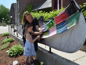 Vanessa May of CNIB Deafblind Community Services and her daughter Heidi, 5, work on a yarn bombing on Tom Thomson's canoe outside the Tom Thomson Art Gallery in Owen Sound on June 4, 2021.