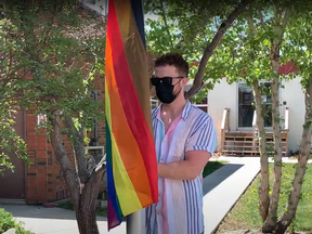 Devon Burgess, wellness centre programmer for the City of Cold Lake, raises the rainbow flag in front of city hall on June 1, 2021.