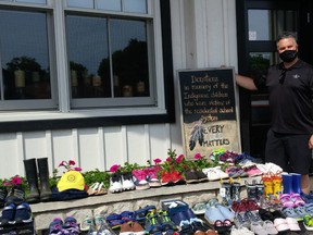 The Walker House general manager Caley Doran, whose mother survived a residential school, stands with a growing collection of children’s shoes in front of the Southampton restaurant with items donated by the public in response to the unmarked graves of 215 children found at a former residential school in British Columbia. [Frances Learment]