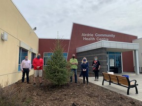 Airdrie Health Foundation Board chair Ryan Thompson (from left to right), Dave Smith from Blue Grass Nursery, Rod Toth and Nicole Glindemann from Precise Pruning, and Virginia Wheeler, site manager for the Airdrie Community Health Centre stand with the newly planted Tribute Tree outside of the Health Centre.