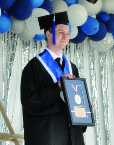Justin Bergen poses with the County Central High School valedictorian medallion during the 2021 graduation ceremony held May 29 outside the Cultural-Recreational Centre. From the podium, Robert Strauss, Palliser school board chair, congratulated Bergen on being this year's valedictorian, and Bergen then picked up the framed medallion from an easel at the back of the stage.