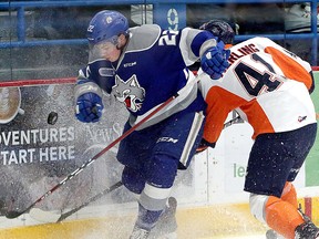 Sudbury Wolves defenceman Jack Thompson (22) shrugs off a hit from Flint Firebirds forward Evan Vierling (41) while clearing a puck along the boards during first-period OHL action at Sudbury Community Arena in Sudbury, Ontario on Friday, February 8, 2019.