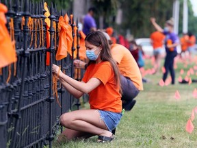 Students and staff from Ursuline College Chatham tie ribbons to a fence in front of the school in Chatham, Ont., on Monday, June 14, 2021, in memory of the 215 children's bodies found buried at the site of a former residential school in Kamloops, B.C. (Malone/Chatham Daily News)