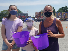 Michelle Franklin, CEO of Epilepsy Southwestern Ontario, right, is shown on Saturday with Clare Gillis, 18, far left, and Mischa Williams, 16, during the drive-thru Ribfest for Epilepsy Southwestern Ontario, held in the parking lot at Memorial Arena in Chatham. (Trevor Terfloth/The Daily News)