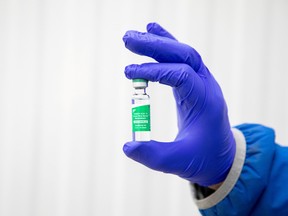 A worker holds a vial of AstraZeneca COVID-19 disease vaccine doses at a facility in Milton, Ont. March 3.