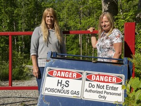 Paula Jongerden and Richelle Spanjers by a sign next to their properties in Norfolk County warning of the putrid smell coming from an old natural gas well about 300 metres away that erupts at least twice a week.