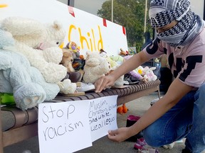 Mohammad Alowdh puts up signs during a drive-by vigil held at the Chatham-Kent Civic Centre on June 17 in honour of the Afzaal family, who were killed in an alleged hate-motivated attack in London earlier in the week. Trevor Terfloth/Postmedia Network