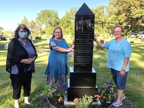 (l-r) Karen Guth, North Norfolk foundation; Janice Wiebe, cemetery chairperson; Arlene Jarema, cemetery treasurer, unveil the new cemetary memorial. (supplied photo)