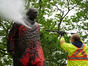 The statue of Sir Winston Churchill near city hall in downtown Edmonton is washed on Thursday June 17, 2021 after it was vandalized with red paint.