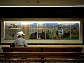 A woman waits for a train at the Grandin LRT Station in Edmonton. In background is a mural depicting the residential school system and Catholic church Bishop Vital-Justin Grandin. Edmonton city council voted unanimously on Monday June 7, 2021 to change the name of the Grandin LRT Station and cover up this mural as soon as possible, following the recent discovery of 215 children who were found in a mass grave on the grounds of a former residential school in Kamloops, B.C.