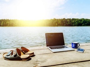 laptop with cup and phone one wooden dock. river on background.