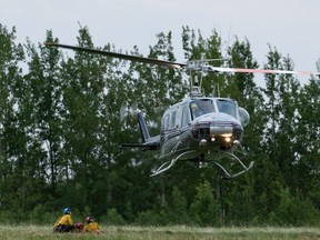 Alberta wildland firefighters work with a helicopter as they battle a wildfire between Evansburg and Wildwood on Tuesday, June 22, 2021.