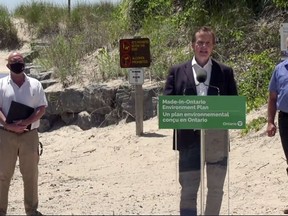 Prince Edward County Mayor Steve Ferguson, left, and Bay of Quinte MPP Todd Smith flank Environment, Conservation and Parks Minister Jeff Yurek during Thursday's announcement at Sandbanks Provincial Park.