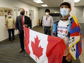 Sangyal Kyab, foreground, holds a Canadian flag presented to him by Liberal MP Neil Ellis, second from left, at Ellis' office Wednesday in Belleville. Supporting Kyab on his Peace Walk for Tibetan freedom were Belleville's Yungdung Gyawatsang, left, and Tenzing Rongtsang, centre.