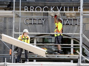 Mackenzie Salmon, left, and Joey Benoit, of Northstar Access, help build a scaffold in front of Brockville's city hall on Monday afternoon, ahead of a longer project to revitalize the building's clock tower. They were among the people still having to do strenuous work amid the current heat wave. (RONALD ZAJAC/The Recorder and Times)