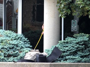 Using a cement pillar for protection, a member of the OPP explosive disposal unit prepares to pick up something to put in a specialized container. The unit was called in after Chatham-Kent police responded to a report of a suspicious package outside of the Judy LaMarsh Building in Chatham on Monday morning. Ellwood Shreve/Postmedia Network