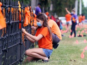 Students and staff from Ursuline College Chatham tie ribbons to a fence in front of the school on Monday in memory of the 215 children's bodies found buried at the site of a former residential school in Kamloops, B.C. Mark Malone/Postmedia Network