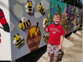 Mack Schellenberger (7-years-old) standing beside his mural. He painted an overflowing honey pot with bees flying around it. Mack has become a beekeeper thanks to the Huron Student Honey project. Submitted