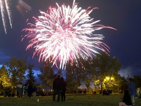 Silhouetted figures stand on the Grande Prairie Regional College campus as fireworks explode over the Muskoseepi Park reservoir to usher in Canada Day on Sunday July 1, 2018