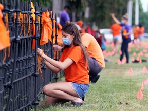 Students and staff from Ursuline College Chatham tie ribbons to a fence in front of the school Monday in memory of the 215 children's bodies found buried at the site of a former residential school in Kamloops, B.C. Mark Malone