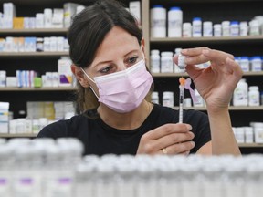 FILE: A pharmacist draws up a dose of the Pfizer-BioNTech COVID-19 vaccine, in Toronto, Friday, June 18, 2021.